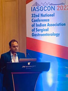 Speaker at a podium giving a lecture at IASGCON 2022 conference banner in Kolkata, JW Marriott venue.