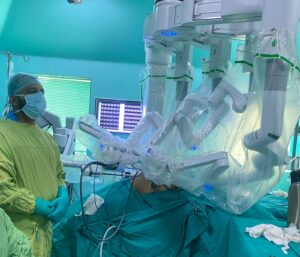 Surgeons operate with a robotic-assisted system in a bright operating room, covered in sterile drapes and gowns.